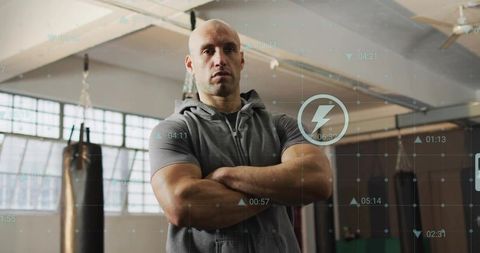 Muscular trainer standing with arms crossed in industrial gym with digital hud overlay