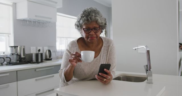 Senior Woman Drinking Coffee and Using Smartphone in Modern Kitchen - Download Free Stock Images Pikwizard.com