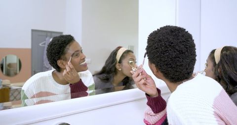 Friends applying eye makeup together at home vanity