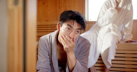 Asian and african american couple relaxing in wooden sauna, intimate wellness scene