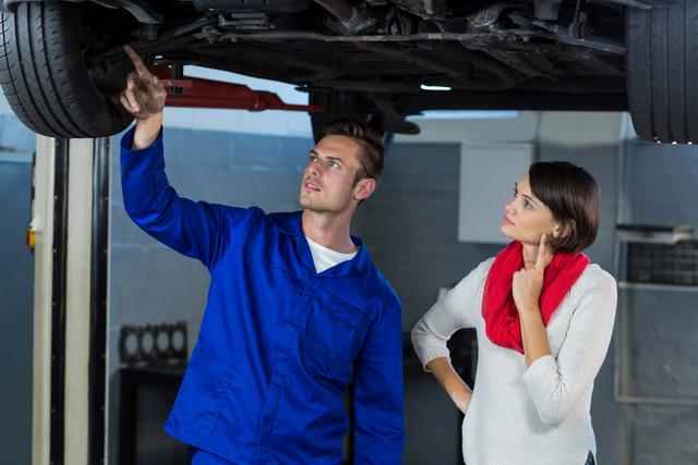 Mechanic showing customer the problem with car in repair garage