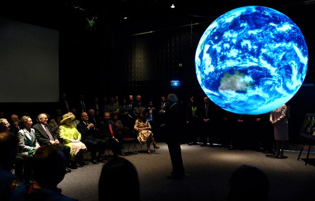 Queen Elizabeth II and Prince Philip, The Duke of Edinburgh look on as Goddard employees demonstrate “Science on a Sphere.” This system, developed by the National Oceanic and Atmospheric Administration (NOAA), uses computers and four video projectors to display animated images on the outside of a 6-foot diameter sphere.  Photo Credit: (NASA/Pat Izzo)