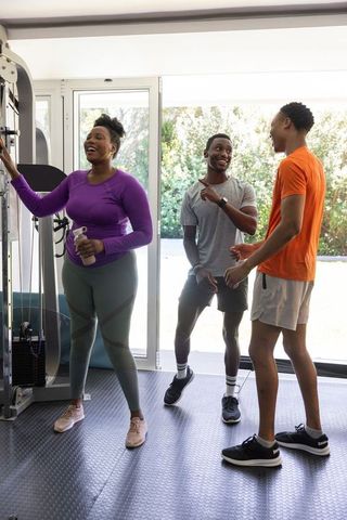 African american friends chatting and laughing in bright home gym during casual workout