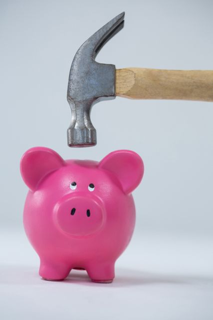This image depicts a pink piggy bank about to be smashed by a hammer, symbolizing financial crisis, risk, or the breaking of savings. It can be used in articles or advertisements related to finance, investment, economic downturns, debt management, or financial planning.