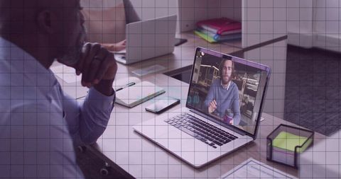 Businessman leaning and watching laptop during remote team meeting in contemporary office space