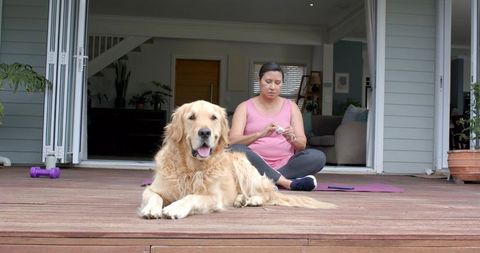 Morning patio yoga and relaxed bonding with golden retriever on wooden deck lifestyle