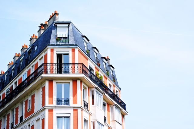 Elegant French apartment building with ornate balconies and windows bordered by blue sky, capturing urban living and European architecture. Suitable for real estate blogs, travel brochures, architectural studies, design inspiration, or promotional materials for tourism in France and Europe.