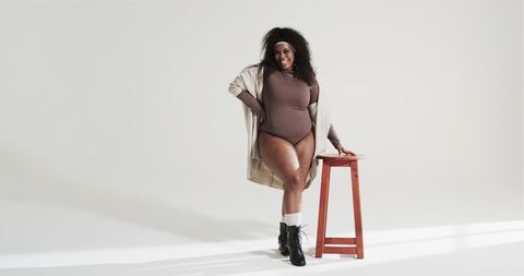 Confident woman posing in fashionable bodysuit with red stool