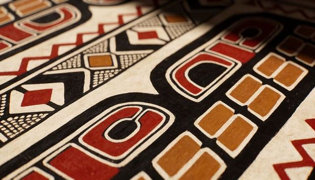 Hand-painted geometric panel featuring bold tribal motifs, visible brush strokes and patina