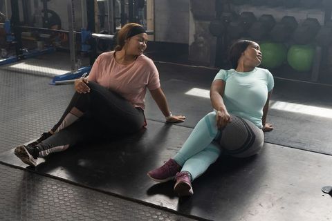 African american women stretching together in gym performing seated spinal twist