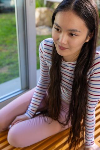Woman in Sunroom Gazing at Garden Showcasing Serenity and Contemplative Lifestyle