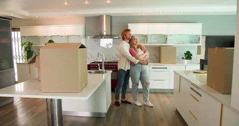 Happy Couple Embracing in New Modern Kitchen During Move