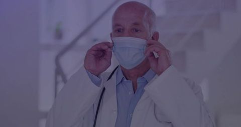 Senior Doctor Adjusting Surgical Mask in Modern Hospital Corridor