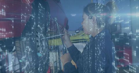 Female mechanic tightening lug nuts on lifted red car wheel wearing navy coveralls