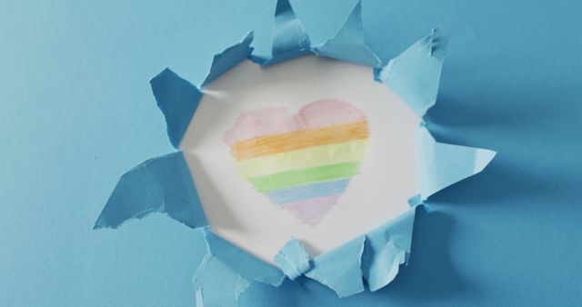 Heart-shaped rainbow illustration emerging from torn blue paper background expresses themes of love, diversity, and LGBTQ pride. Artistic torn paper design adds a unique touch. Ideal for use in Pride Month promotions, LGBTQ-inclusive content, and creative projects symbolizing love and equality.