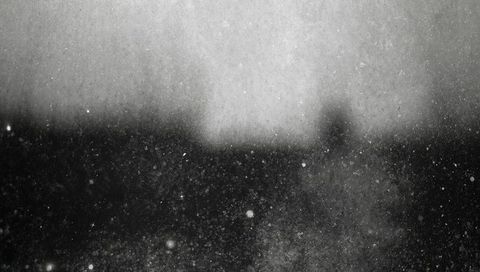 Scattering dust and grain on dirty glass over blurred outdoor horizon, monochrome texture