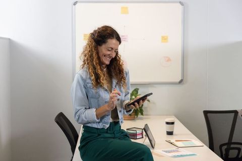 Smiling professional woman using tablet on meeting table in modern office