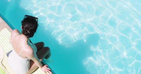 Woman Relaxing Poolside in Sunlight with Beach Hat