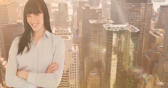 Digital composition of businesswoman standing with arms crossed against cityscape in the background