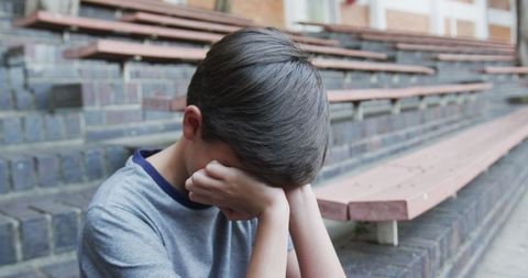 Young Boy Sitting on Bleachers Resting at School