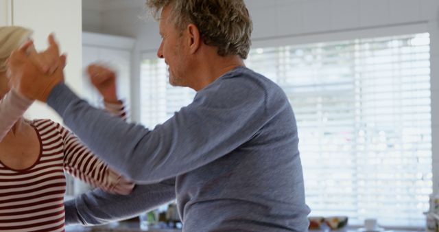 Side view of mature caucasian couple dancing together in kitchen at home - Download Free Stock Photos Pikwizard.com