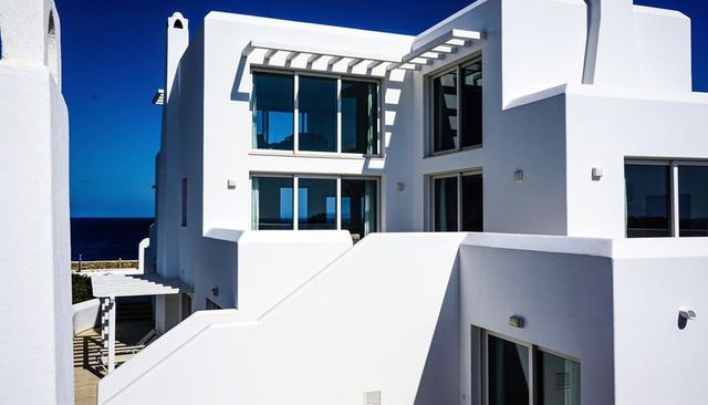Minimalist white coastal villa with cubic design, glass windows and ocean view, terrace