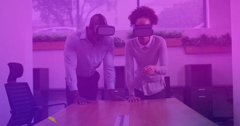 Colleagues collaborating in virtual reality headsets at modern conference table