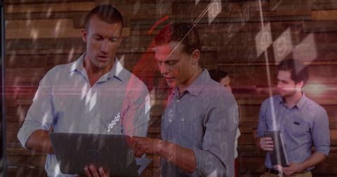 Two professionals collaborating over laptop with data overlays in modern workspace