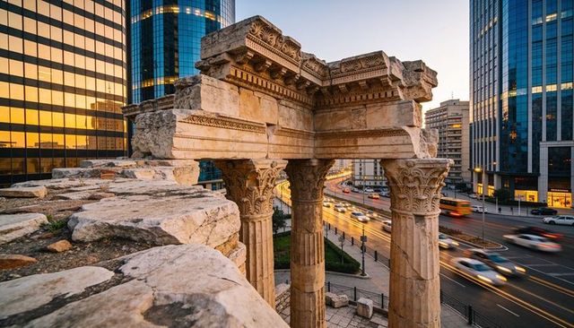 Ancient corinthian columns standing amid modern downtown skyline at sunset with light trails