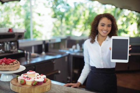 Happy Café Attendant Displaying Tablet at Artisan Bakery