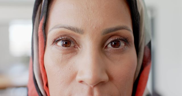 This close-up image of a person's face wearing a hijab features striking, expressive eyes under natural light. Ideal for use in projects emphasizing eye contact, human emotion, cultural diversity, or detailed portraiture. Suitable for blogs, articles, promotional materials, or inclusivity campaigns.