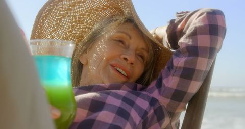Senior Woman Relaxing with Cocktail at Beach