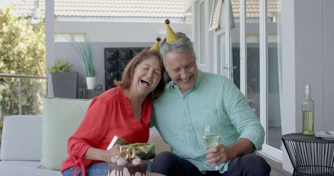 Senior Couple Joyfully Celebrating Birthday with Cake and Wine