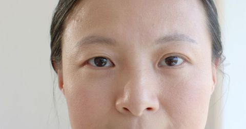 Tight close-up of asian woman looking directly at camera showing natural skin texture