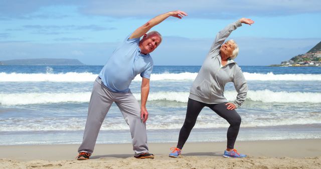 A senior Caucasian couple is engaging in stretching exercises on a sandy beach, with copy space - Download Free Stock Photos Pikwizard.com