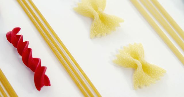 Image showcasing different types of uncooked pasta including bow-tie, fusilli, and spaghetti laid out on a white background. Useful for recipes, cooking blogs, food packaging design, culinary articles, or restaurant menus illustrating pasta varieties.