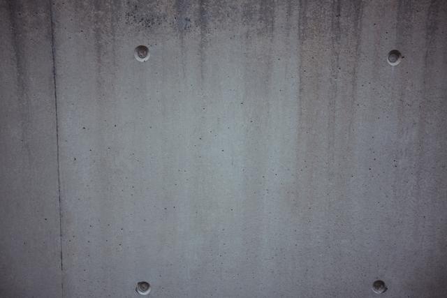 This image showcases a close-up of a weathered concrete wall, ideal for use as a background in various projects. Its grunge texture and gray tones make it suitable for industrial design themes, website backgrounds, and digital art. The aged and rough surface can also serve as an excellent reference for artists or designers creating realistic textures.