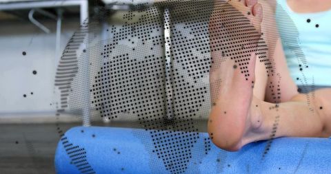 Resting woman placing bare feet on blue foam roller closeup with halftone dot overlay