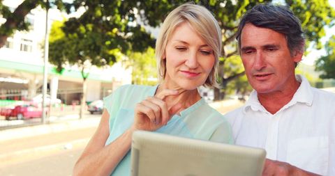 Mature Couple Using Tablet Outdoors in Urban Setting