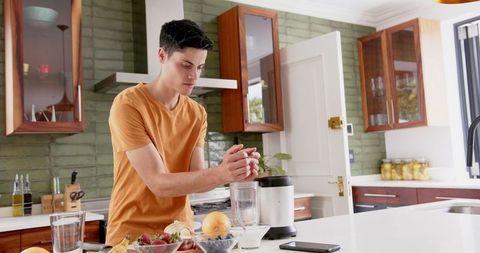 Man Preparing Fresh Fruit Smoothie in Modern Kitchen