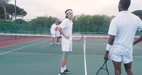 Tennis doubles players showing kinesiology tape on thigh during outdoor har-tru match