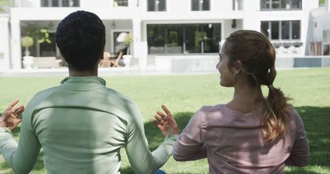 Lesbian Couple Meditating Together Outdoors in Sunny Garden