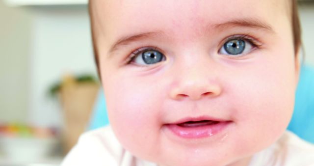 Close-up of a baby with blue eyes and flushed cheeks, smiling sweetly. Perfect for advertisements, parenting blogs, baby product promotions, and family-oriented articles. Captures the essence of childhood innocence and joy, ideal for any content that focuses on early childhood development, parental care, or baby wellness.