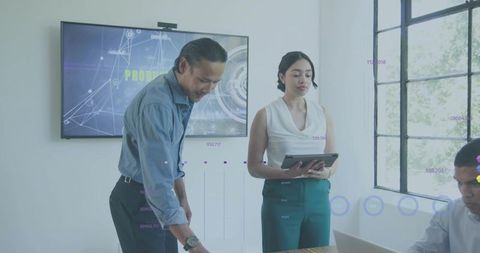 Asian businesswoman reviewing tablet during collaborative meeting in bright boardroom
