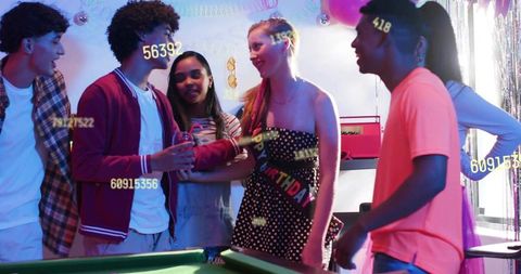 Smiling celebrant in strapless dress wearing birthday sash with friends at pool table