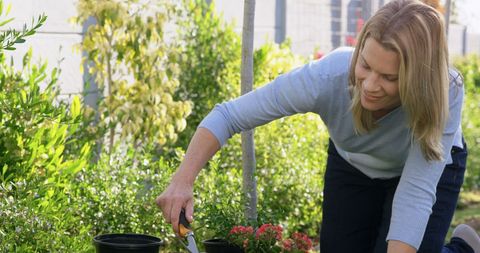 Woman Enjoying Gardening in Lush Backyard