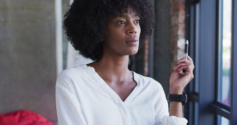 Thoughtful Young Woman with Stylish Hair Holding Pen