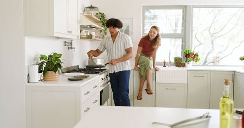 Young Couple Enjoying Leisurely Cooking in Sunlit Kitchen