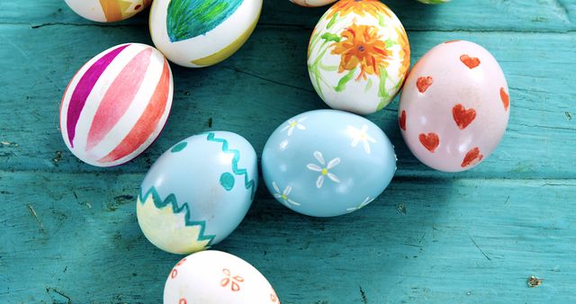 Colorfully decorated Easter eggs are arranged on a vibrant blue wooden surface, with copy space. These eggs, adorned with various patterns and designs, symbolize the festive spirit of the Easter holiday.