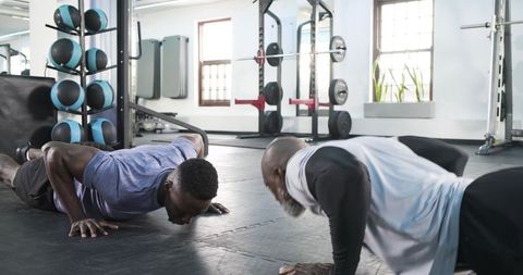 Two men training with push-ups in modern gym environment